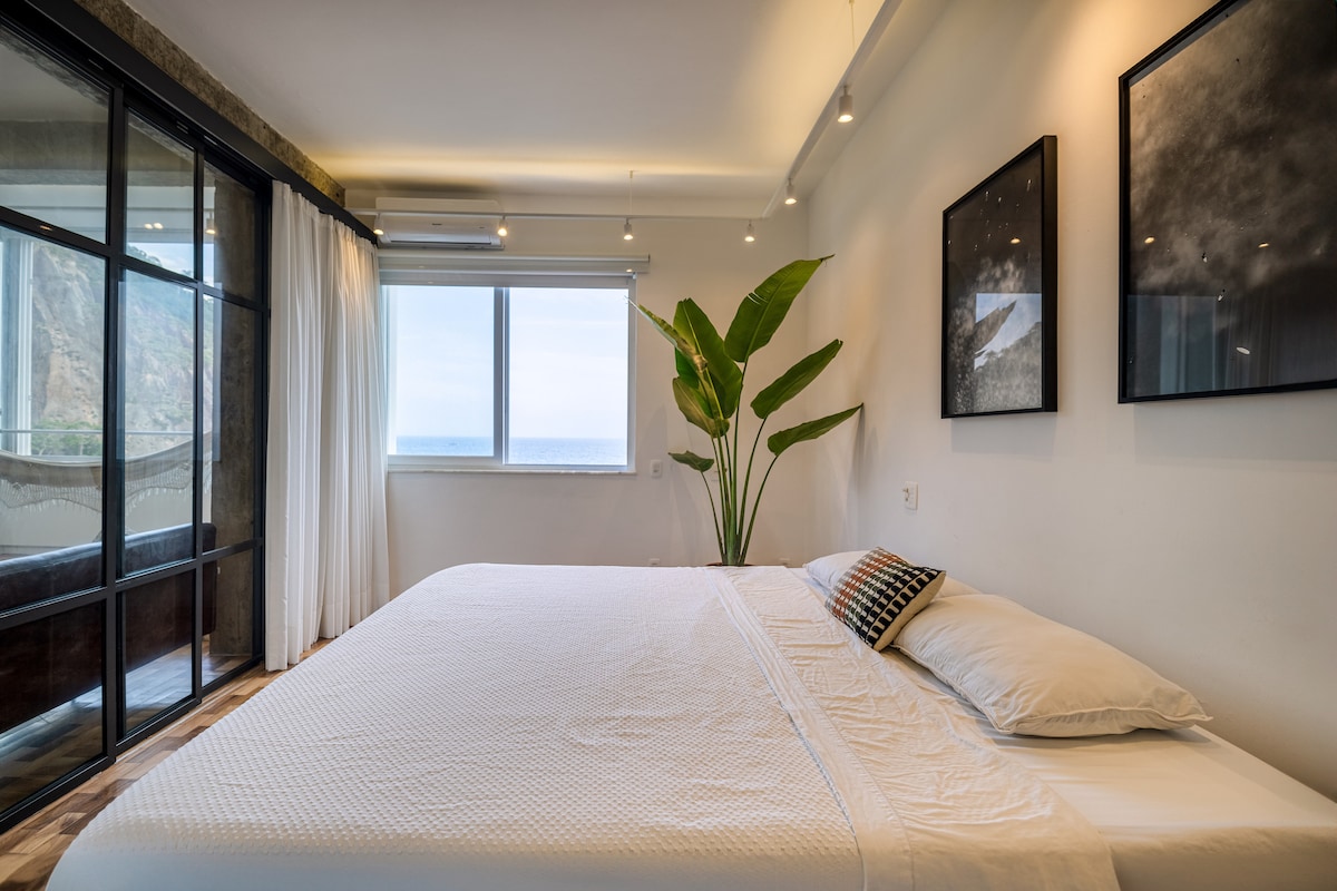 Quarto com cama king, plantas e vista para o mar